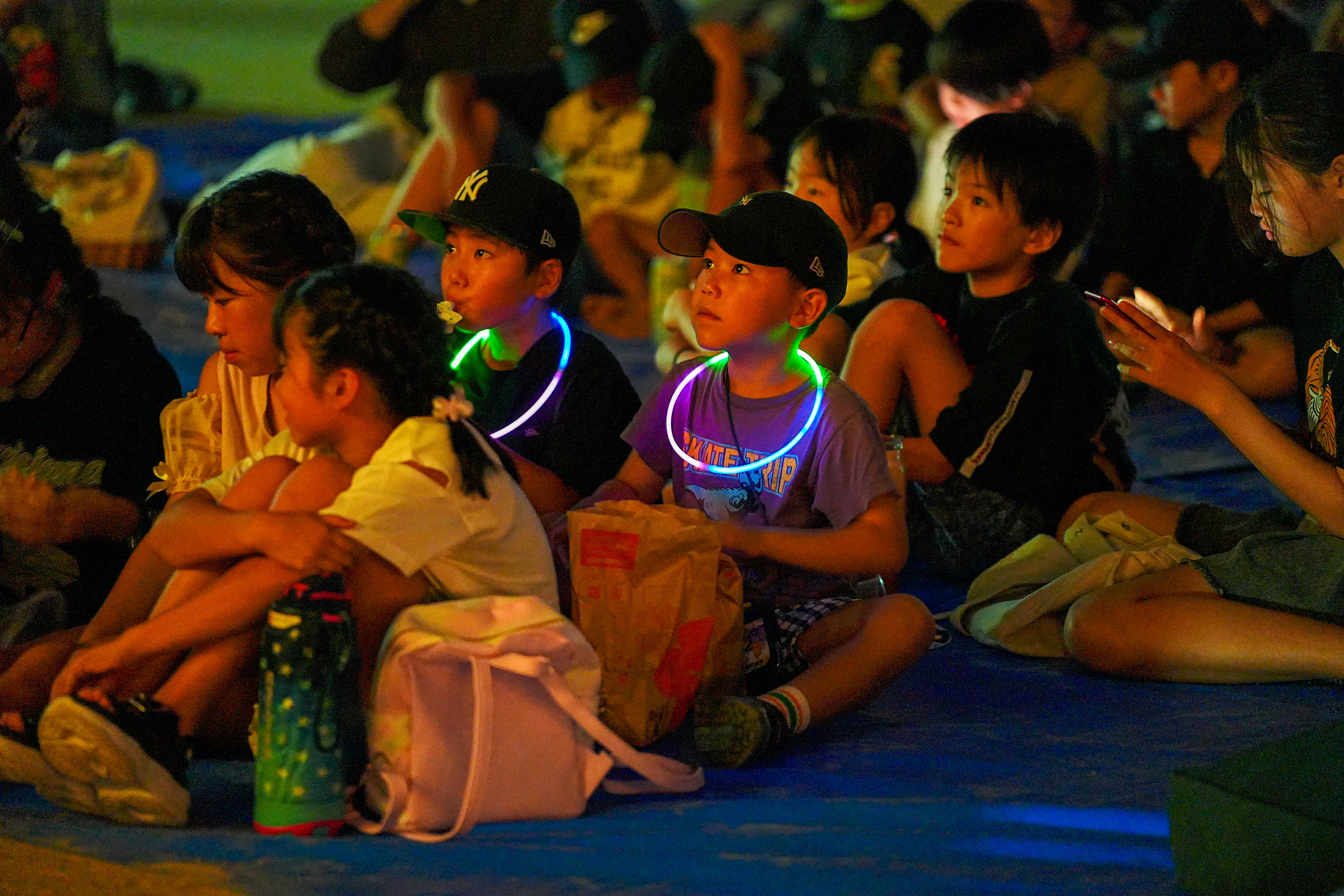 光るネックレスをつけて映画を観る子どもたち